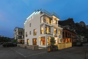 A modern hotel with multiple floors, large windows, and a well-lit facade.