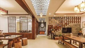 A spacious living area with a wooden dining table, benches, a fireplace, and a TV. - Tingxiju Inn (Xianju)