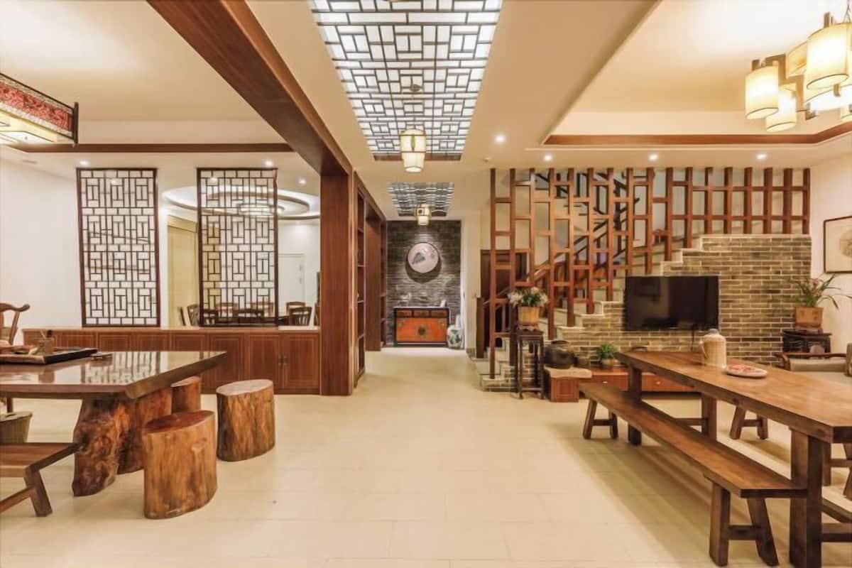 A spacious living area with a wooden dining table, benches, a fireplace, and a TV.