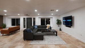 Een moderne woonkamer met een modulaire bank, een salontafel en een flatscreen televisie aan de muur.