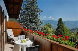 A balcony with a table, chairs, and a view of mountains.