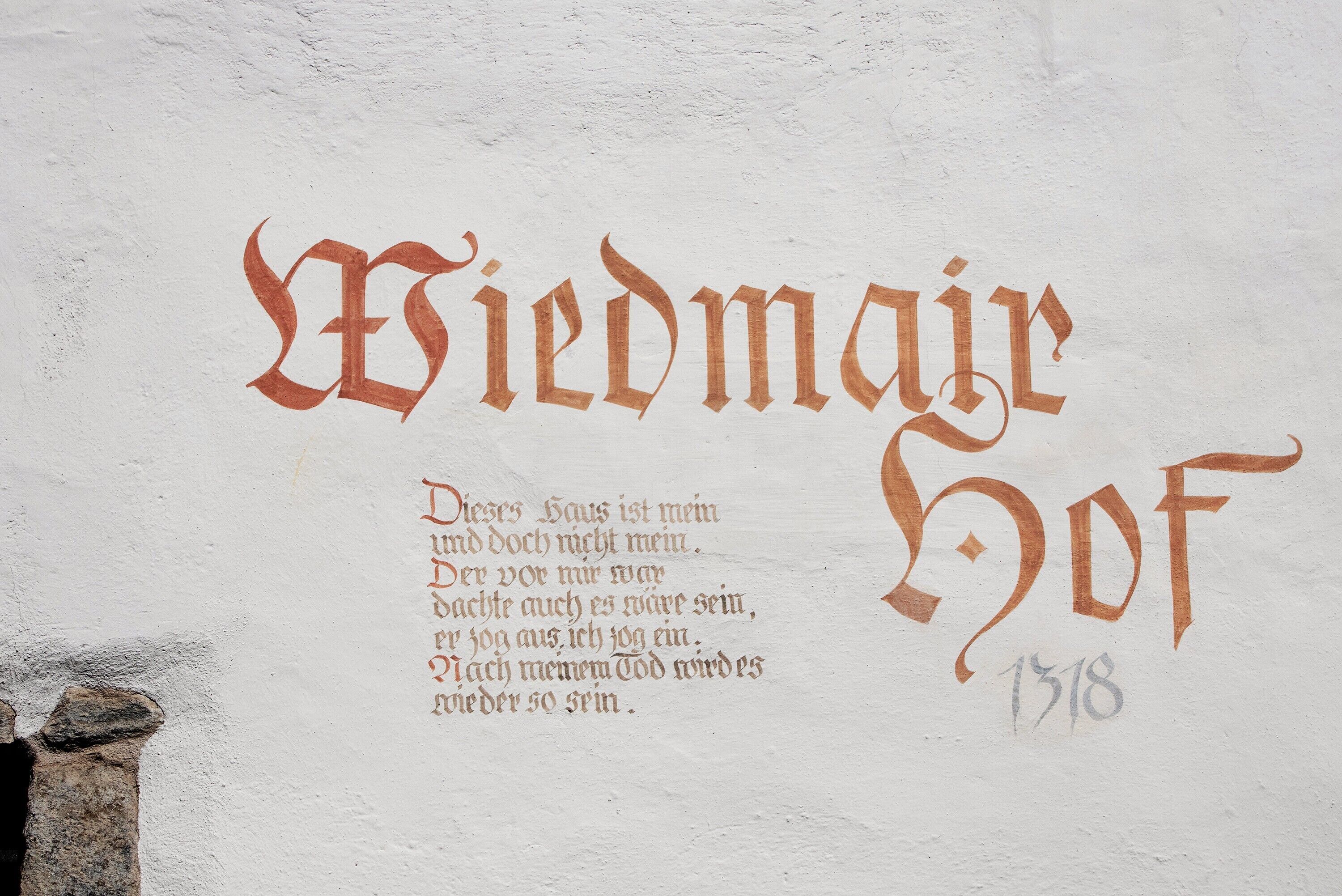 A wall with the text 'Wiedmaire Hof' and a poem in German, with the year '1518' below.