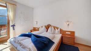 A bedroom with a bed, bedside tables, a window with curtains, and wall-mounted lights.