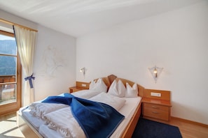Une chambre à coucher comprenant un lit, des tables de chevet, une fenêtre avec des rideaux et des lampes fixées au mur.