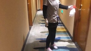 A person in a hallway with patterned carpet, wooden doors, and a wall-mounted light switch. - Anna Baige Hotel (Shanghai)