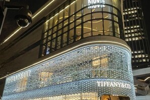 A building facade with a Tiffany & Co. sign, a curved glass structure, and a modern design. - Anna Baige Hotel (Shanghai)
