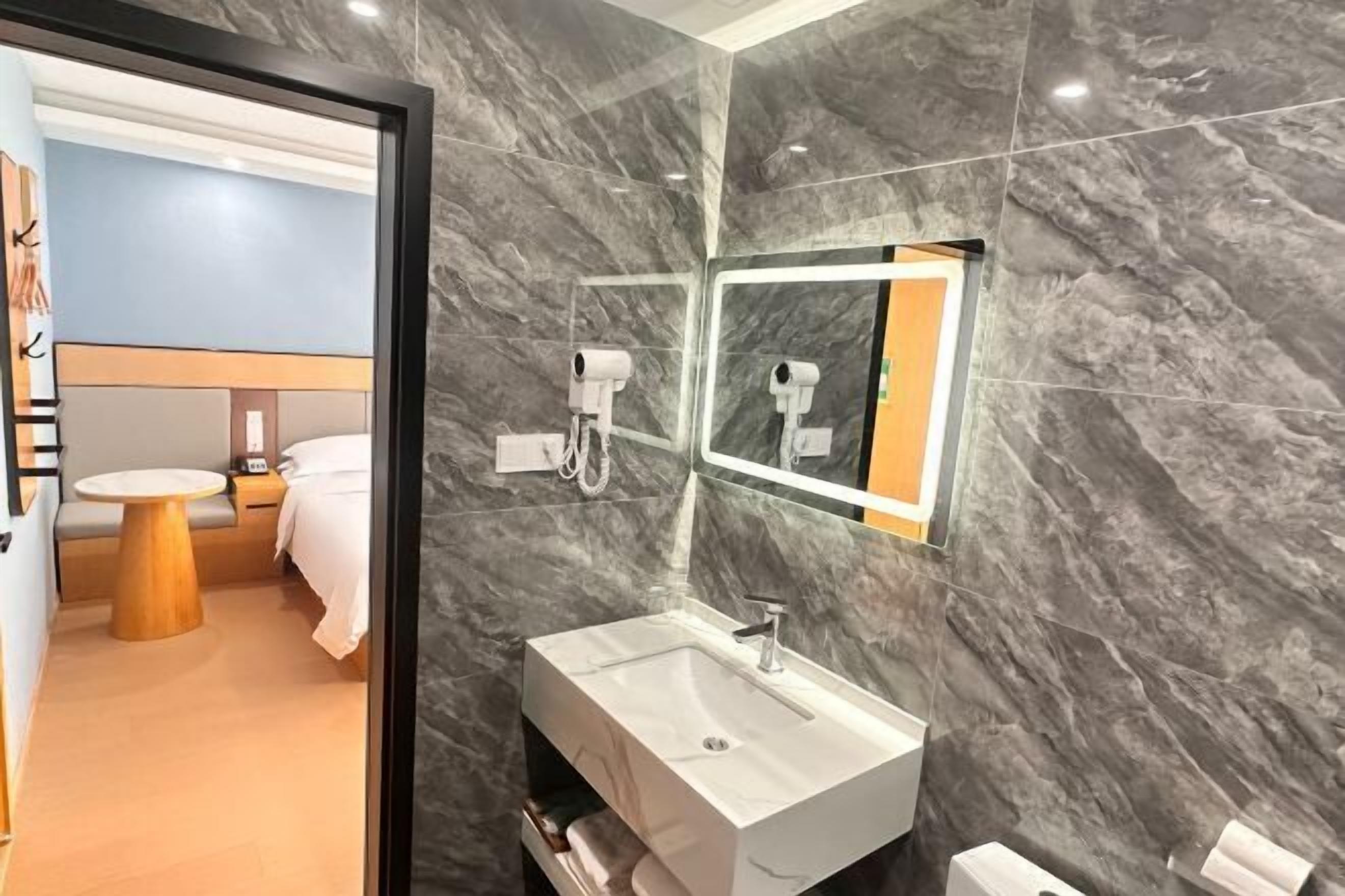 A modern bathroom with a marble wall, a large mirror, a sink, and a hairdryer.