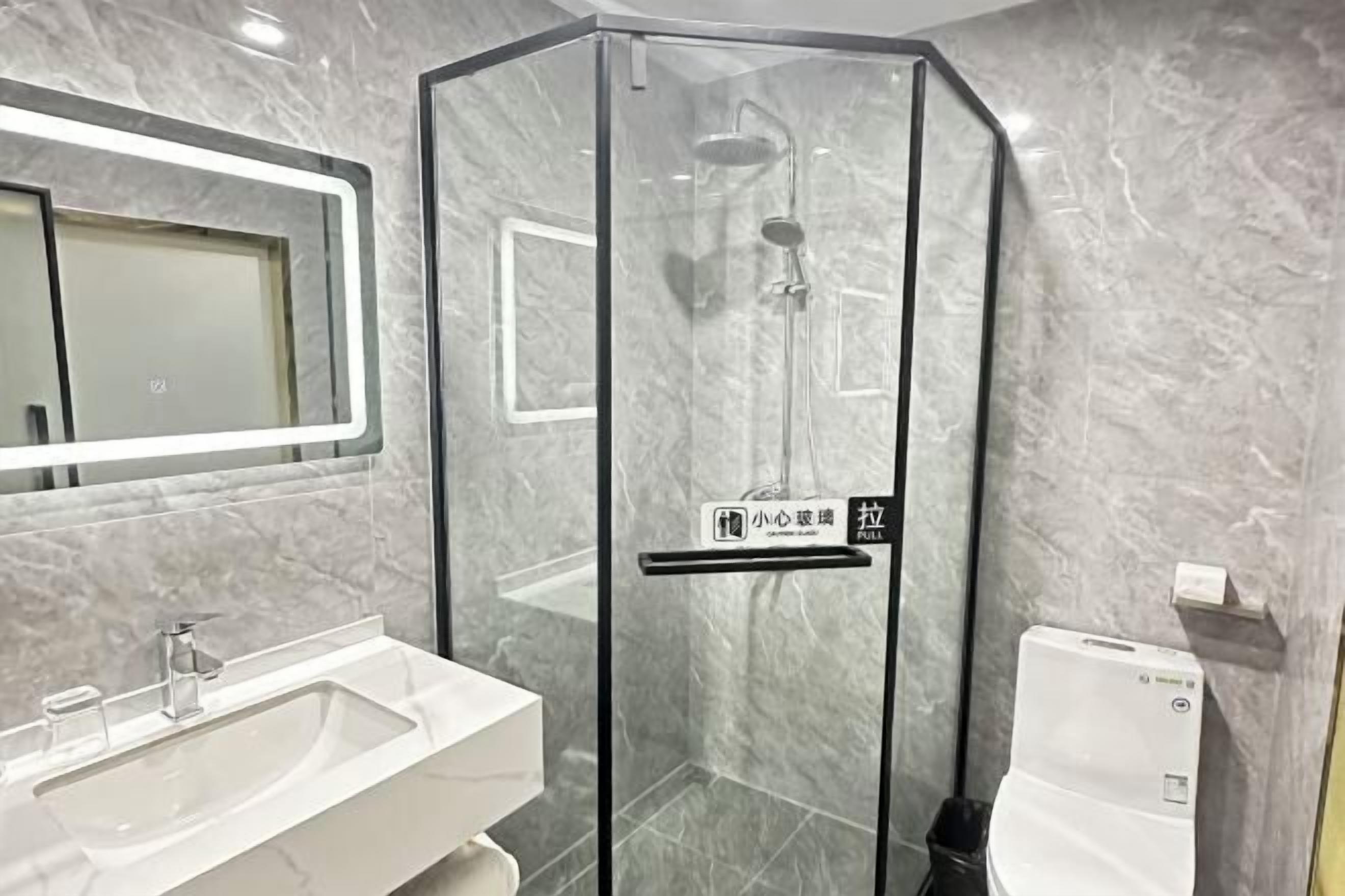 Ein modernes Badezimmer mit einer gläsernen Dusche, einem Waschbecken und einer Toilette.