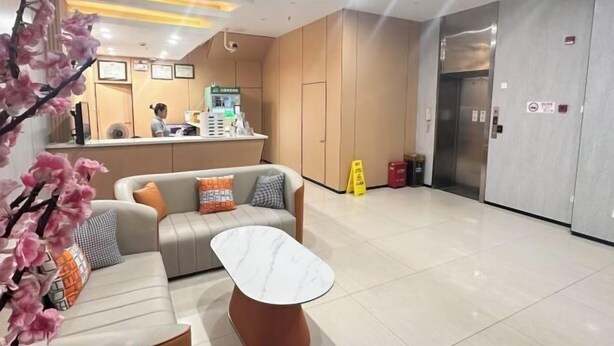 A hotel lobby with a reception desk, a sofa, a coffee table, and an elevator. - Anna Baige Hotel (Shanghai)