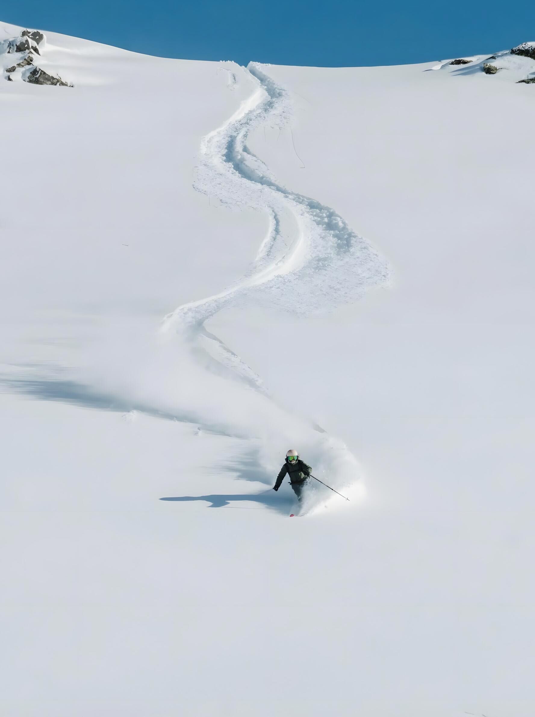 A snowy mountain slope with a ski trail.