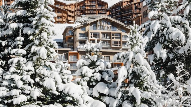 A snow-covered lodge with multiple balconies and a mountainous backdrop. - Apartment '6p Au Pied Des Pistes' with Mountain View, Balcony and Wi-Fi (Val Thorens)