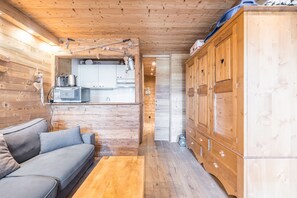 Un interno in legno con un divano, armadietti e angolo cottura.
