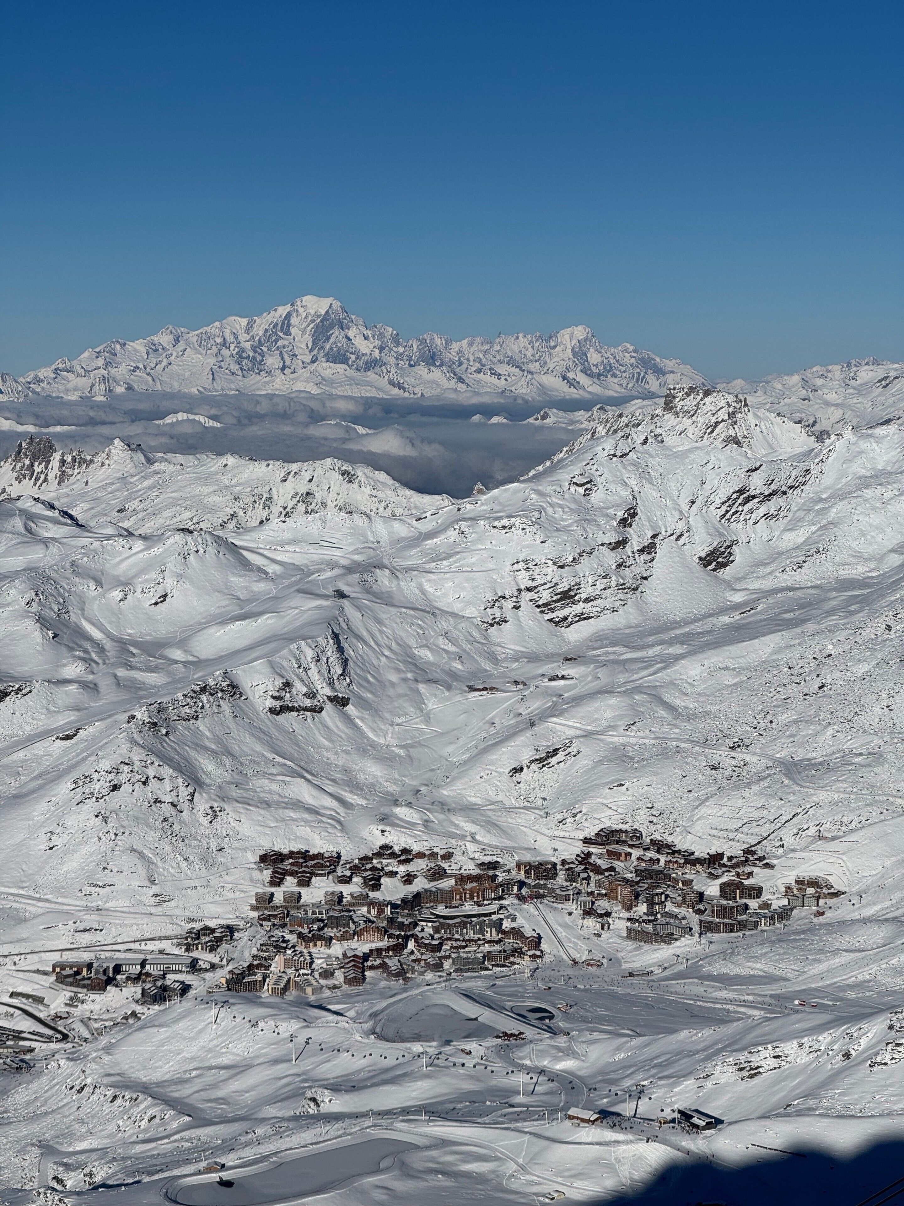 A snow-covered mountainous landscape with a town in the foreground featuring traditional buildings and winding roads.