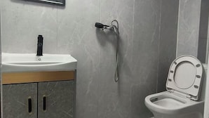 A bathroom with a sink, mirror, toilet, and shower. - Xinyue Hotel (Taiyuan Ophthalmology Hospital) (Taiyuan)