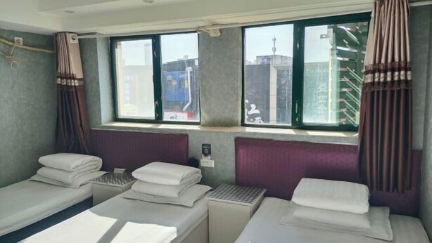 A hotel room with two single beds, a window with a view of buildings, and a small table with a lamp. - Xinyue Hotel (Taiyuan Ophthalmology Hospital) (Taiyuan)