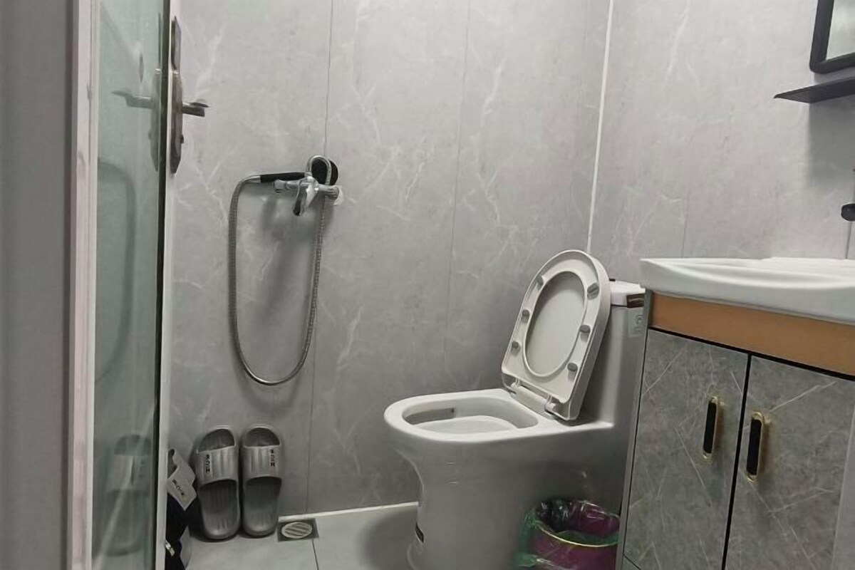 A bathroom with a toilet, a shower, and a sink.
