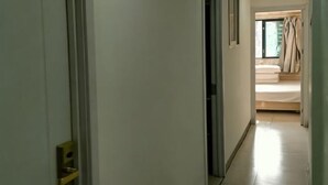 A hallway leading to a bedroom with a bed, a window with curtains, and a door with a handle. - Xinyue Hotel (Taiyuan Ophthalmology Hospital) (Taiyuan)