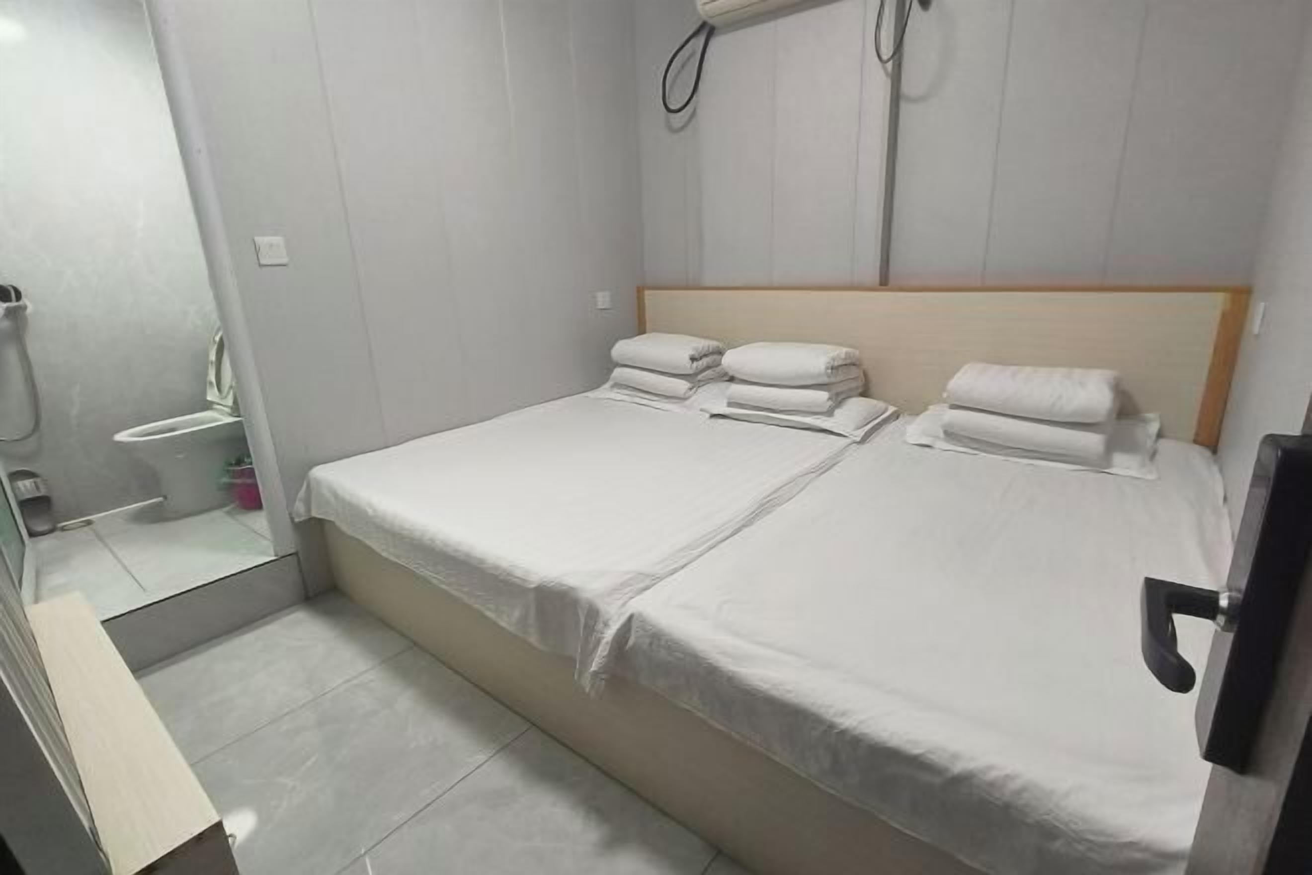 A hotel room with a double bed, two pillows, a bedside table, and a mirror.