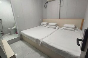 A hotel room with a double bed, two pillows, a bedside table, and a mirror. - Xinyue Hotel (Taiyuan Ophthalmology Hospital) (Taiyuan)