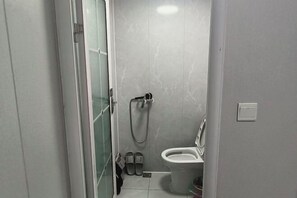 A small bathroom with a toilet, a shower, and a glass door leading to a hallway. - Xinyue Hotel (Taiyuan Ophthalmology Hospital) (Taiyuan)