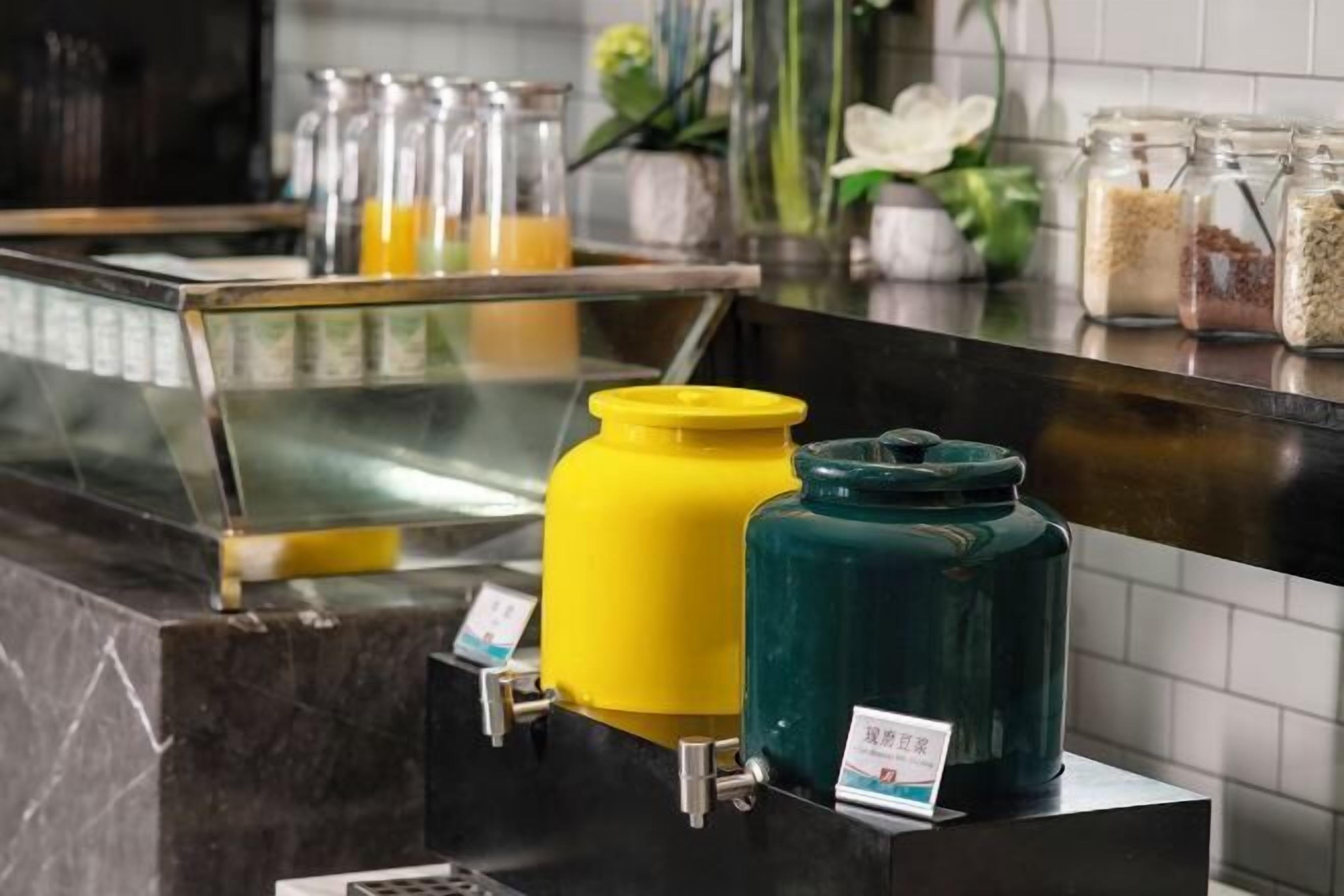 Una estación autoservicio de bebidas con dispensadores y una variedad de alimentos en frascos.