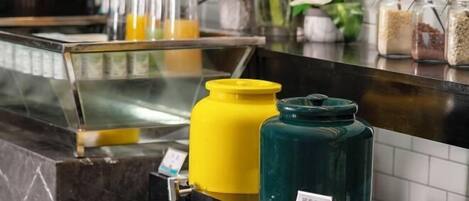 Una estación autoservicio de bebidas con dispensadores y una variedad de alimentos en frascos.