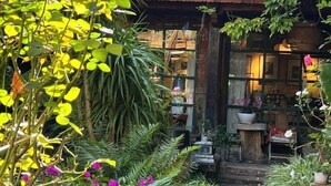 A traditional Japanese-style building with a tiled roof, surrounded by lush greenery and potted plants. - Yunguichu Chain Inn (Jianchuan)
