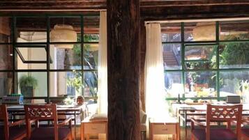 Un comedor con muebles de madera, ventanas amplias y vista a la vegetación exterior.