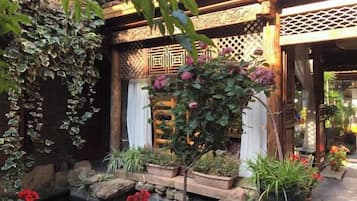 A traditional Japanese-style garden with a wooden structure, potted plants, and a small water feature.