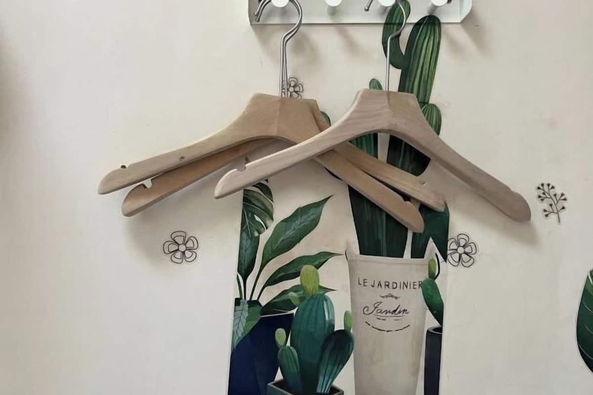 Un mur orné d’un cactus et d’un porte-manteau en bois suspendu, auquel est attachée une étiquette portant l’inscription « LE JARDINIER ».