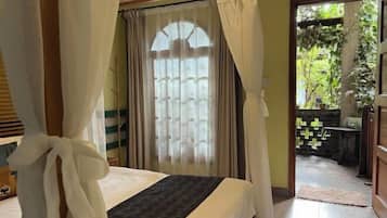 A bedroom with a bed, curtains, and a view of a garden through a window.