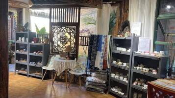 A room with shelves of ceramics, a small table, and a chair.