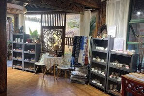 A room with shelves of ceramics, a small table, and a chair.