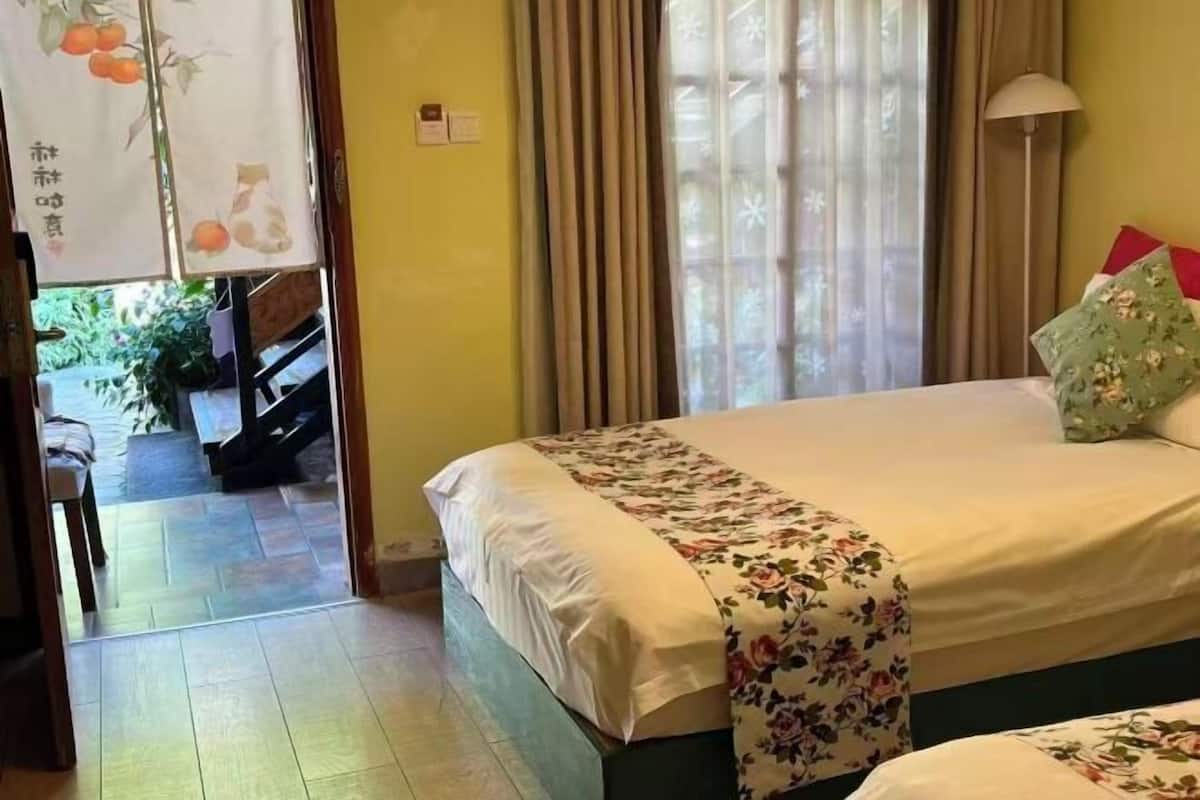 Une chambre d’hôtel avec un lit, une fenêtre avec des rideaux, une lampe et une vue sur l’extérieur.