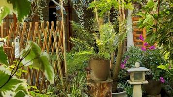 A garden with a wooden fence, various potted plants, and a bird feeder.