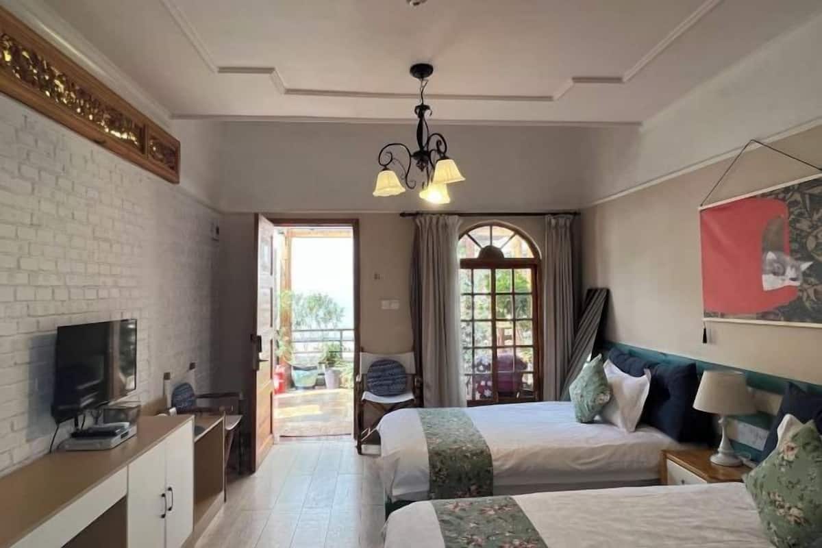 Une chambre d’hôtel avec deux lits, une télévision, un bureau et un balcon avec vue.