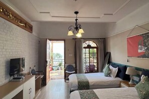 Une chambre d’hôtel avec deux lits, une télévision, un bureau et un balcon avec vue.