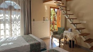 A bedroom with a bed, a chair, a small table, a staircase, and a view of the outdoors. - Yunguichu Chain Inn (Jianchuan)