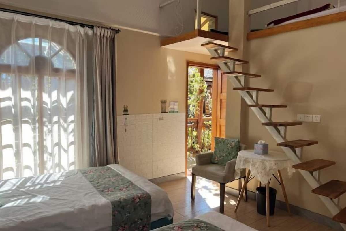 Une chambre à coucher comprenant un lit, une chaise, une petite table, un escalier et une vue sur l’extérieur.