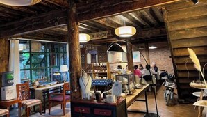 A rustic interior with wooden beams, a bar area, and a seating space with tables and chairs. - Yunguichu Chain Inn (Jianchuan)