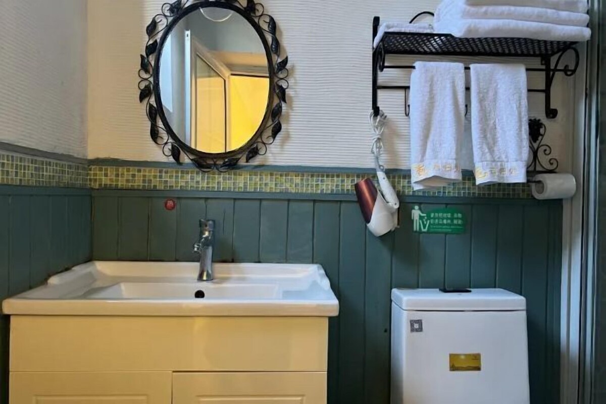 A bathroom with a sink, mirror, towel rack, and a sign indicating a smoking area.