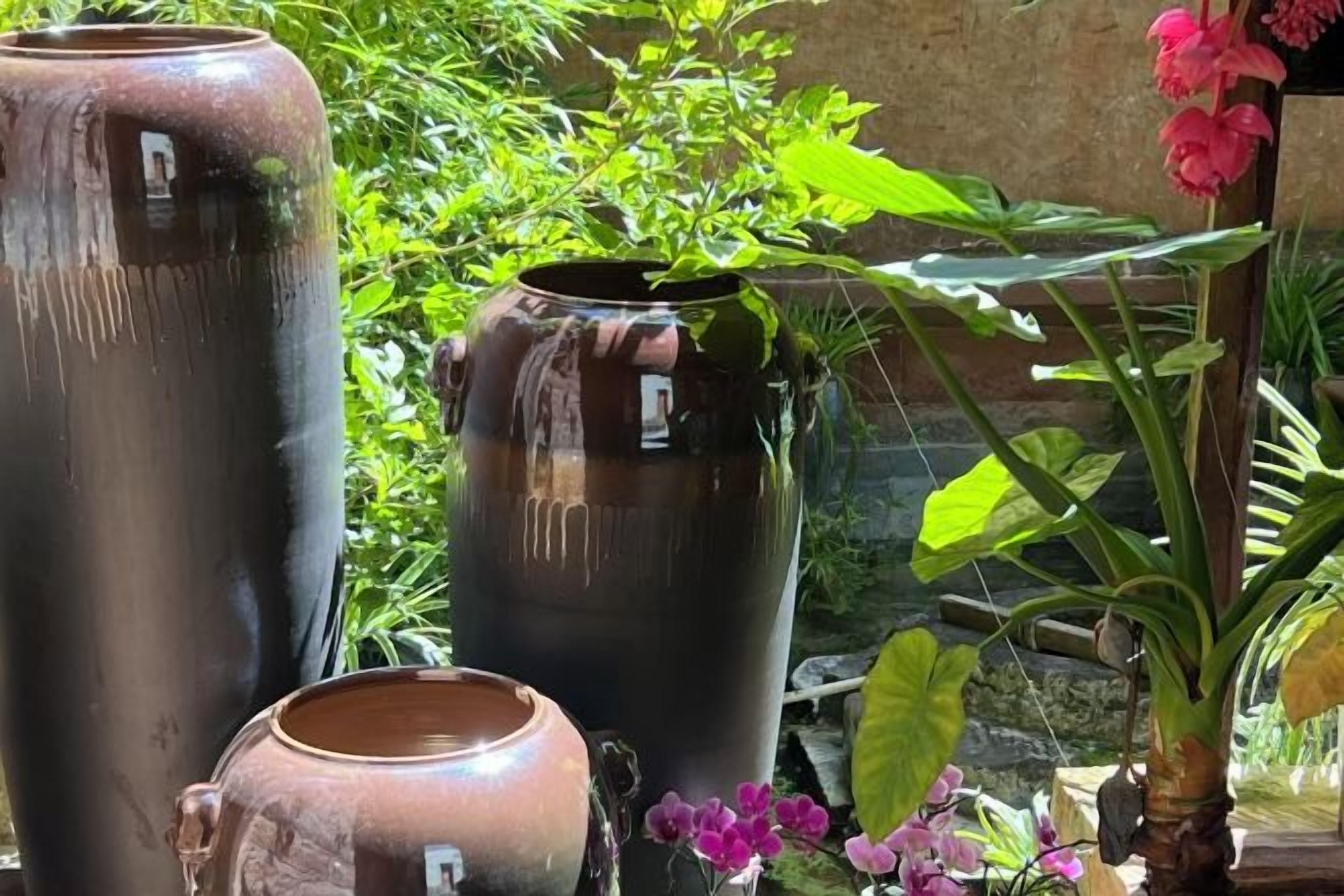 Large ceramic pots in an outdoor setting with greenery.