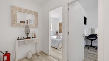Quarto com cama, mesa de cabeceira, espelho e porta para outro cômodo.