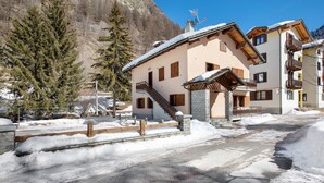 Ein Gebäude mit einer Treppe, die zu einem Balkon führt, umgeben von Schnee und Bäumen.