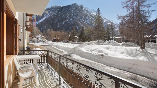 Ein Balkon mit Blick auf verschneite Berge und Bäume.