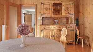 Ein Holzinterieur mit einem runden Tisch, einem Blumenstrauß und einer Vitrine mit Zierverzierungen.