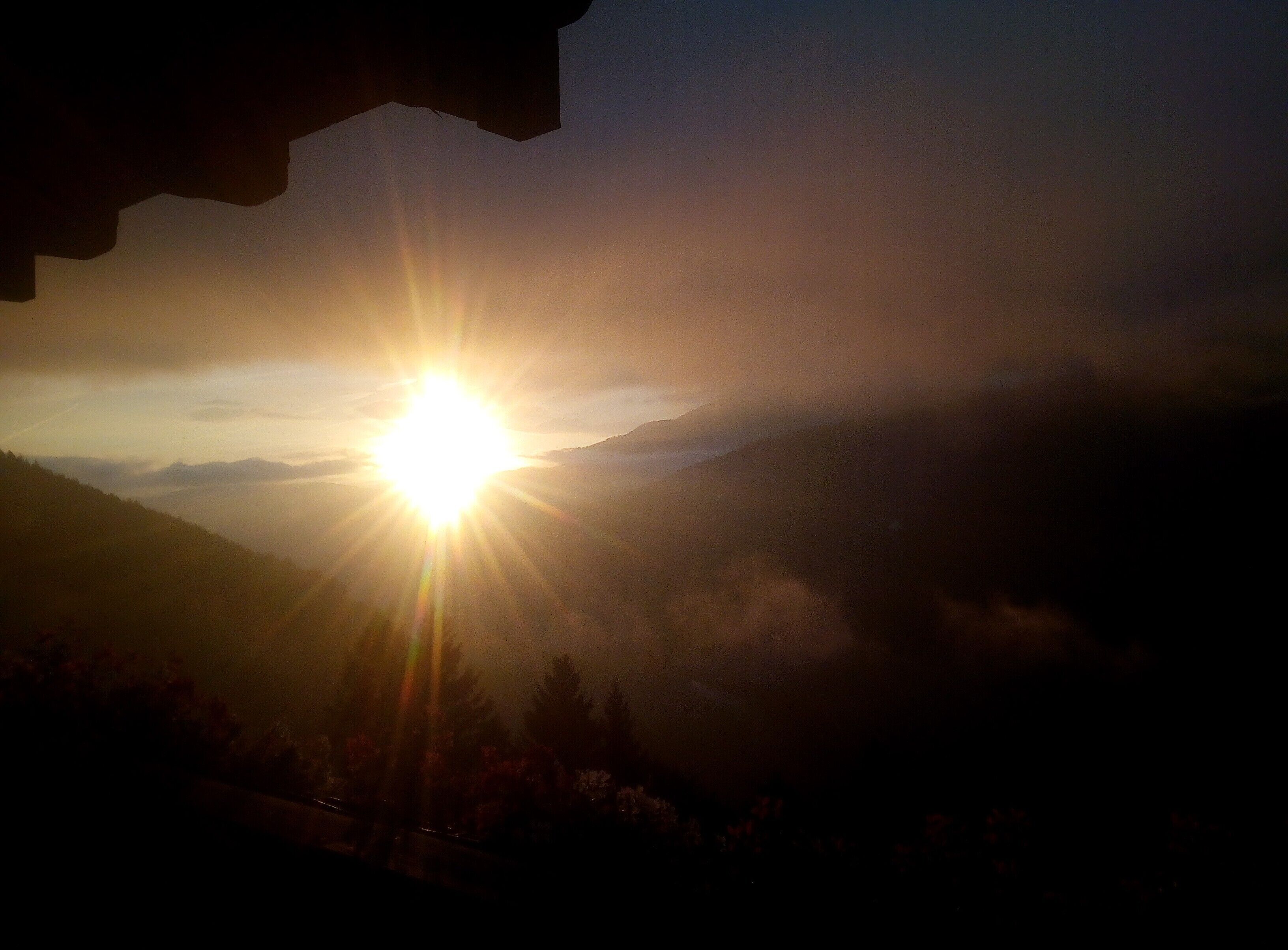 Un lever de soleil sur un paysage montagneux, avec un ciel dégagé.
