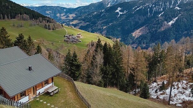 A mountain lodge with a wooden exterior, a covered patio, and a view of a valley and snow-capped mountains. - Chalet 'Niederhaushof  Edelweiß' with Mountain View, Private Garden and Wi-Fi (Ulten)