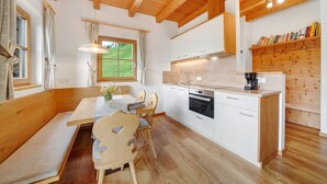 A modern kitchen with wooden beams, a dining area with a bench, and a bookshelf. - Chalet 'Niederhaushof  Edelweiß' with Mountain View, Private Garden and Wi-Fi (Ulten)
