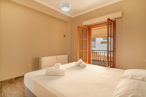 Une chambre d’hôtel avec un lit, une fenêtre donnant sur un paysage agréable et une porte menant à un balcon extérieur.